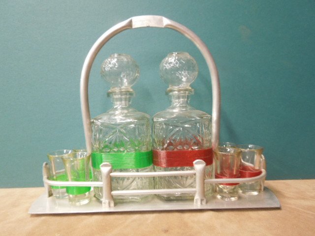 Art Deco Tantalus Set: Art Deco Tantalus set, aluminum frame with handle holds two pressed glass decanters & six shot glasses with green & red banding, early to mid 20th C. [40] 15" x 12" x 5" CONDITION: No issues identifie