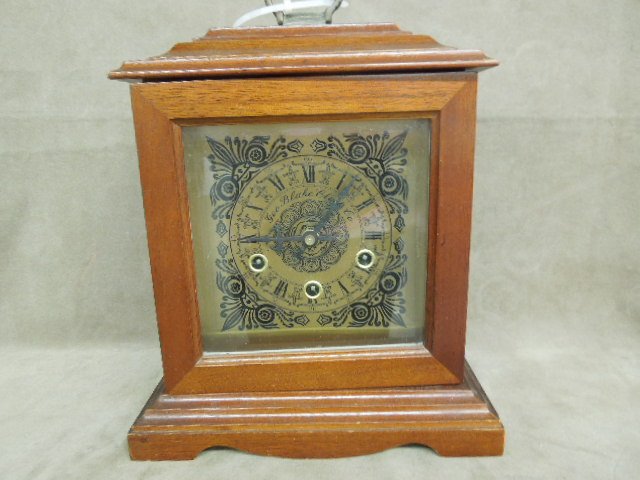 Mahogany Case Mantle Clock: Mahogany case mantle clock, Geo. Blake Clock Co., floral decorated brass face plate, hinged front door, time,strike & chime movement, brass handle at top, with key. CONDITION: Minor surface wear & los