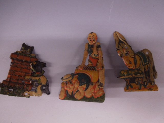 3 German tin Action Clickers by "Gelxi": Three German tin action clickers, by "Gelxi", includes: man with rolling pin on sailor (189); feeding donkey (190); dog after cat on brick wall, early 20th c., 3" to 3 3/4" h. CONDITION: Normal wear,
