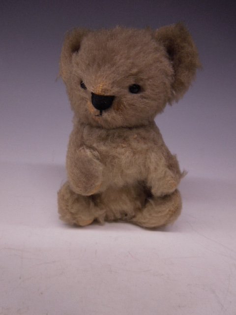 Teddy Bear Cub: Teddy bear cub, made in England, cloth label, gray mohair, black glass eyes, black embroidered nose & mouth, bear in seated position, early to mid 20th C., 6"h. CONDITION: Plush wear on ears, snout, l