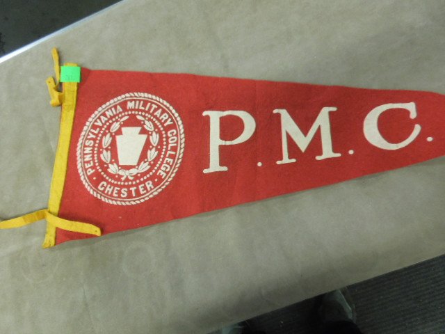 PA Military College Pennant: PA Military College Pennant. P.M.C with Keystone and Laural Leaf 29". CONDITION: Holes in edge and tip and on end ties, minor wear.
