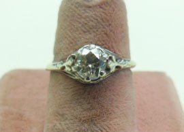 14k WG Deco Diamond Ring: 14k WG Deco Diamond Ring. 14k WG tested, high prong set filigree setting supports an approx 60pt solitaire diamond, yellow color, slight inclusions under 10x loupe. 1.3 DWT size 5 1/4. No appraisal. C