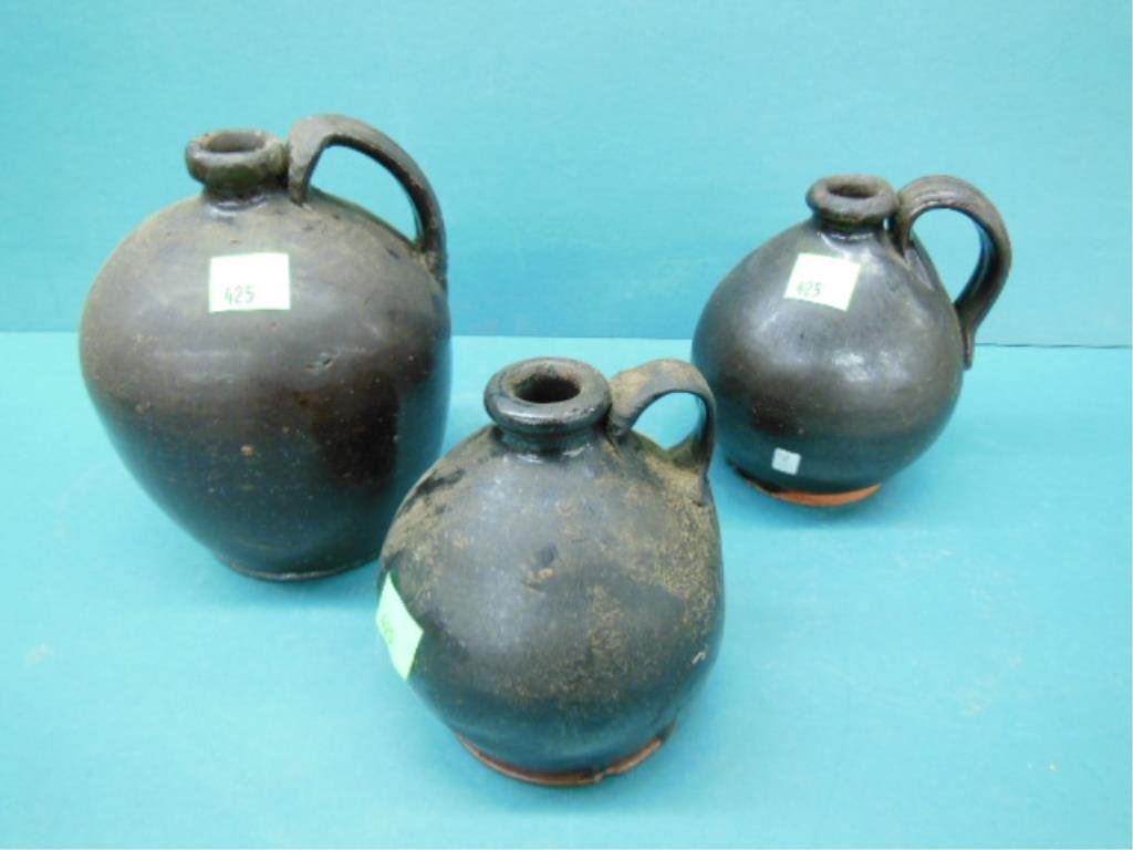 Three 19th c. Redware Jugs: Three 19th c. Redware jugs, in dark brown glazes, all with handle on bulbous bodies, all from digs in Phila., Pa. CONDITION: 9" with repaired and built up handles and lips; 7" with areas of glaze loss