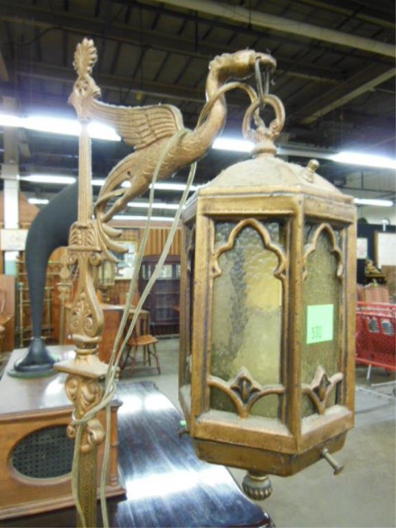 Pr Floor Lanterns: Pair floor lanterns, brass and cast metal columns with winged griffin crests supporting hexagonal lanterns with amber glass panels, bases in cast shell and floral urn pattern, early 20th c. H 65 3/4".