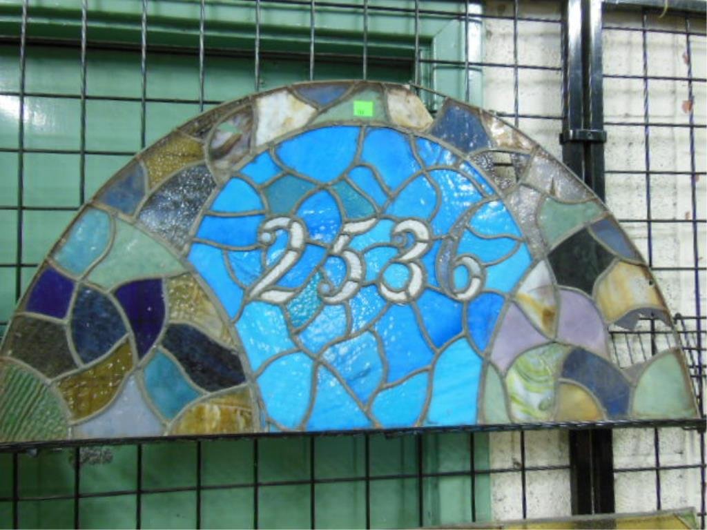 Leaded Glass Transom Window: Leaded glass transom window, arched blue, green, yellow & purple, with address #2566, 42 1/2" l x 22 1/2" h, late 19th C. CONDITION: Many pieces on right side have cracks or loss, a few on the left.
