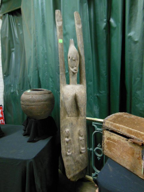 Dogon Figure: Dogon figure on iron stand, from Mali, female with raised arms & solid base with relief carved totems, figure 59" h. [10] CONDITION: Natural rough wood bottom, roughness on top of head.