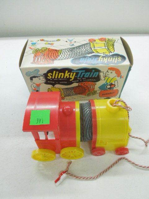 Slinky Train pull toy: Slinky Train pull toy, No. 200 by James Industries "watch it wiggle, watch it stretch", red and yellow locomotive with Slinky toy in middle, string pull with whistle end, 8" with original box Conditio