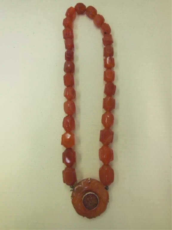 Carved Carnelian Choker Necklace: Carved Carnelian choker necklace, 14k yellow gold & carved 1 1/4" medallion clasp connects 14" strand of carved carnelian faceted beads. Marked WL 14k. CONDITION: Very good vintage, some chips on bead