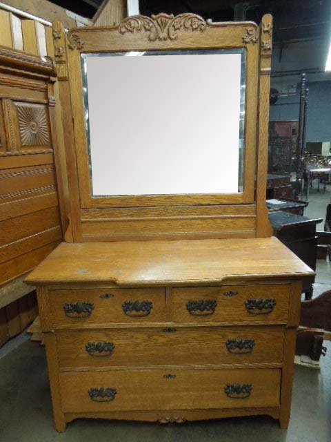 Golden Oak Dresser With Swivel Mirror: Golden Oak dresser, two drawer over two with decorative drawer pulls and escutcheon plates, beveled swivel mirror with carved leaf accents at top. CONDITION: Minor surface wear from age and use, mirro