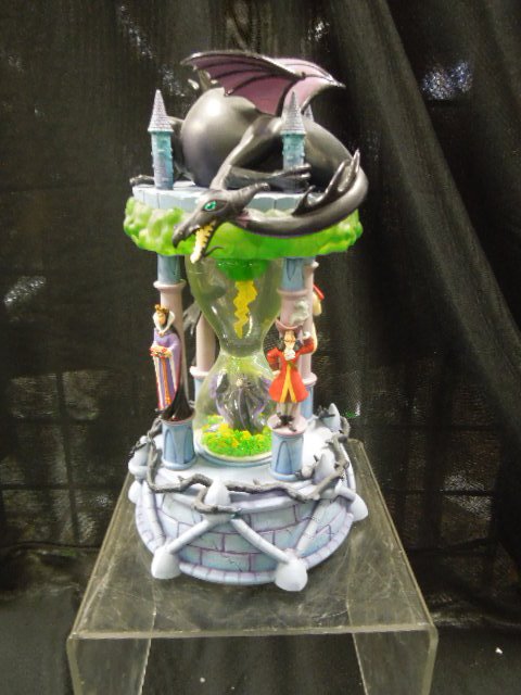 Disney Villains Hour Glass Snowglobe: Disney snowglobe featuring: Maleficent stirring up the elements with other evil villains surrounding on pillars, Dragon curled around turrets at top. Light and sound with original packing box 7" x 12"