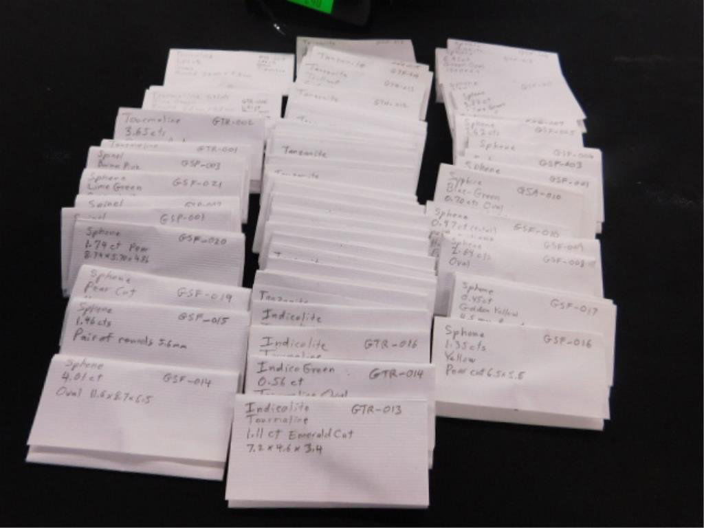 Case of Gems.: 52 packets, some with muptiple gems many larges sizes in black case including sphene, spinel, variouos colors of tourmaline, tanzanite, etc.