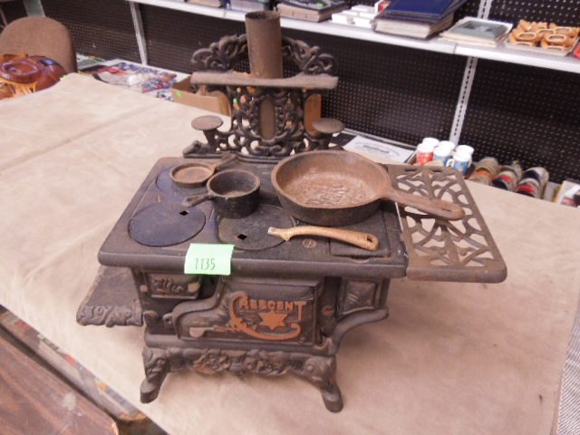 Vintage Crescent Metal Toy Stove: Vintage crescent metal toy stove, iron with stove plate handle, Beks and frying pan, stack in back, 7" x 13 1/2" x 11 1/2" (including stack). CONDITION: Minor surface wear and rusting.