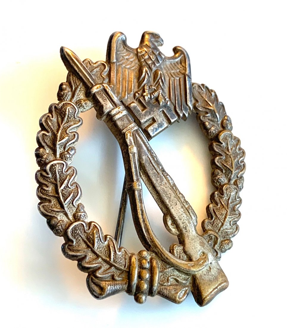 GERMANY WEHRMACHT INFANTRY ASSAULT BADGE: An oval shaped oak leaf wreath, with a national eagle clutching a swastika on the top and a bowtie on the bottom. Diagonally across the badge is a Karabiner 98k with the bayonet attached to the front 