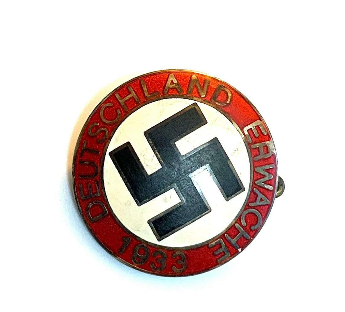 GERMAN NAZI DEUTSCHLAND ERWACHE 1933 LAPEL PARTY BADGE: The front reads 'Deutschland Erwache 1933'. Has a swastika in the center. The reverse side is maker marked 'RZM M1/129'. Has a thin horizontal safety pin back. Nickel construction with enamel.