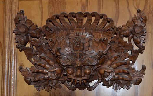 Indonesian Balinese Garuda Wood Carving: Bali, Indonesia, circa 20th century; an intricately detailed, fine hardwood carving, depicting a Garuda mask with outstretched claws amidst floral sprays.