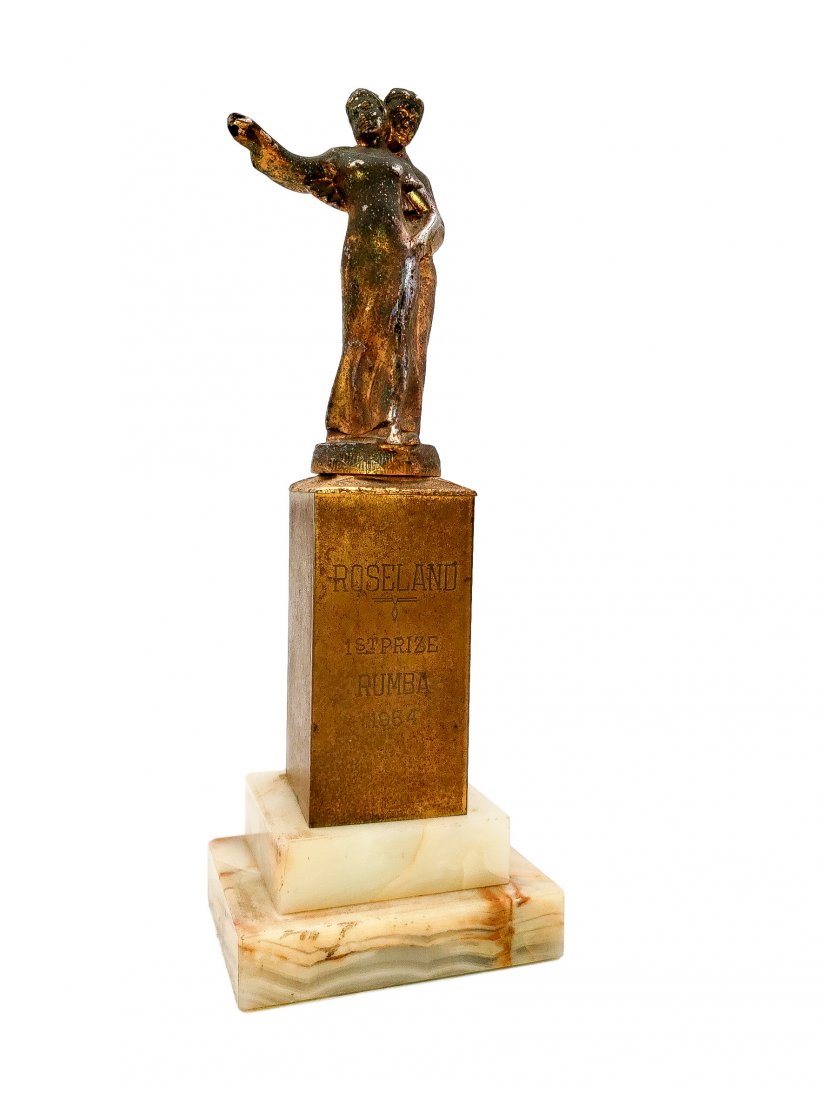 Trophy - 1954 Roseland 1st Prize Rumba: Copper wash metal dancing couple atop a two-step marble plinth base. Engraved plate reads " Roseland: 1st Prize : Rumba: 1954" Storage patina and handling/age wear noted. 3 x 4-inch base 11 inches hig
