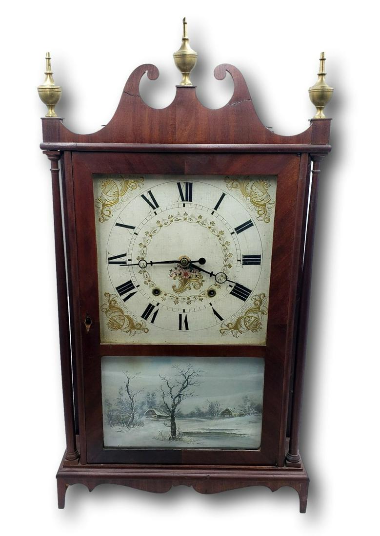 American Mahogany Pillar and Scroll Mantel Clock by Eli Terry: Early 1800s American mahogany pillar and scroll mantel clock with carved scrolled pediment, brass finials, original works, and tapered feet. The clock has the original paper label. Eli terry and Sons,