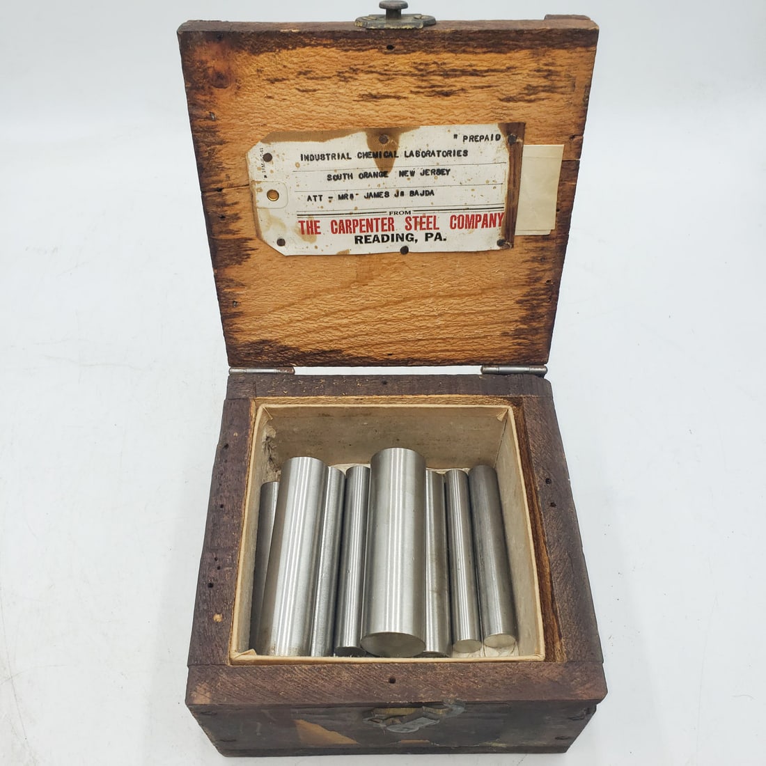 1944 Stainless Steel Bar Stock Samples in Original Wood Box: Wood box labeled The Carpenter Steel Company, Reading PA with 11 stainless steel sample rods inside with an inventory sheet (3 rods are missing according to the inventory sheet). The box is soli