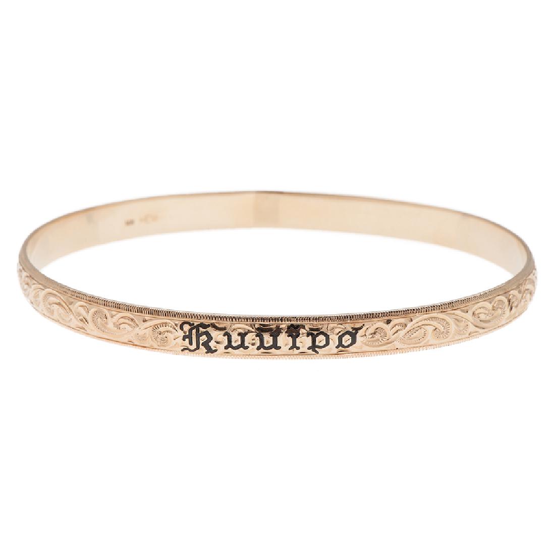 Hawaiian Kuuipo Sweetheart Bangle Bracelet in 14 Karat: Featuring an engraved scroll design and reads "Kuuipo" ("my sweetheart") in black enamel to front. Measures 6mm wide with an interior measurement of approximately 8". 12.9 dwt.