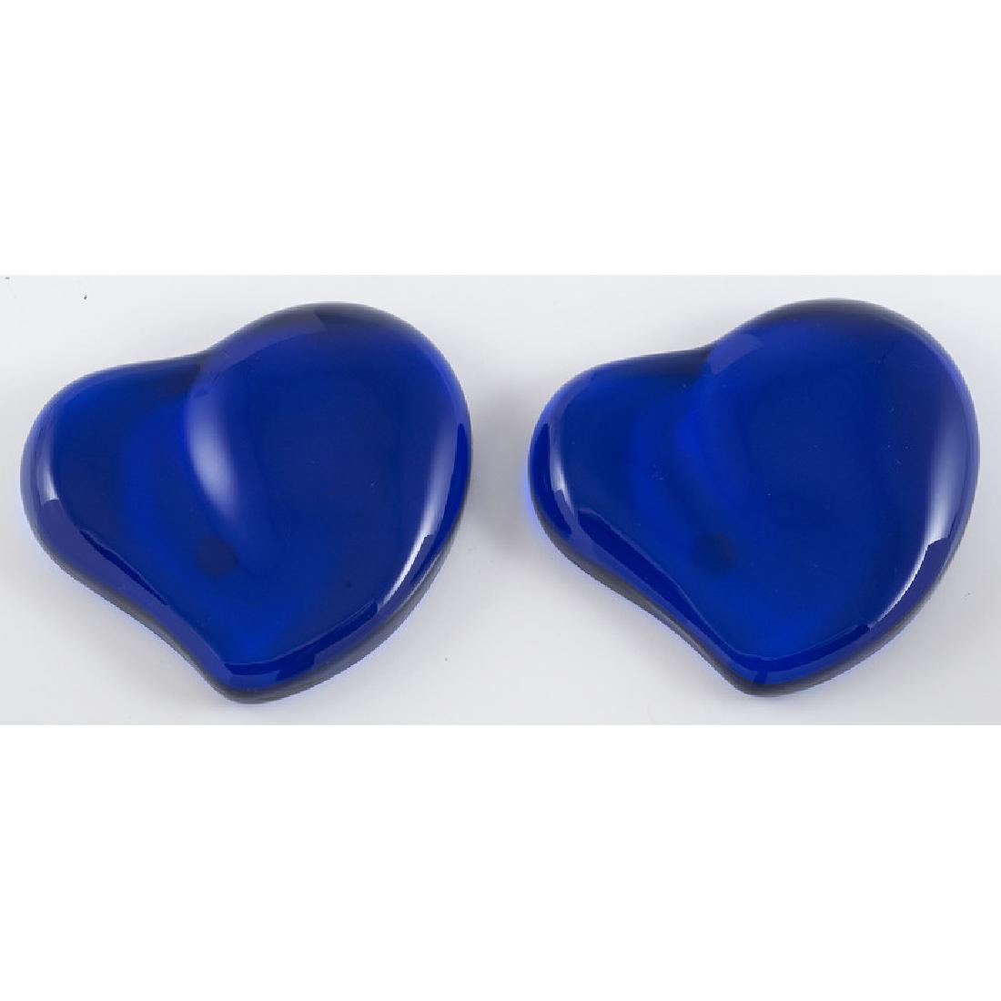 Elsa Peretti for Tiffany & Co. Heart Paperweights: A pair of Elsa Peretti for Tiffany & Co. blue glass heart paperweights. Includes two boxes and one pouch. Measures 4" x 3.75" Provenance: Property from the Collection of Dr. M. Donald Hayes. To Be