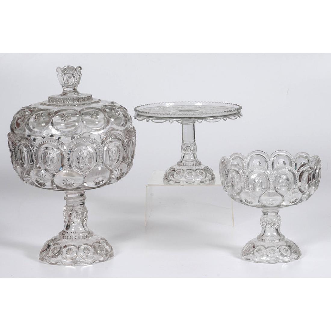 American Pressed Glass Compotes and Stand: 20th century. Two matching compotes, one lidded, and a cake stand; largest oah. 15.5 in. Provenance: Property from the Collection of Dr. M. Donald Hayes. To Be Sold Without Reserve.