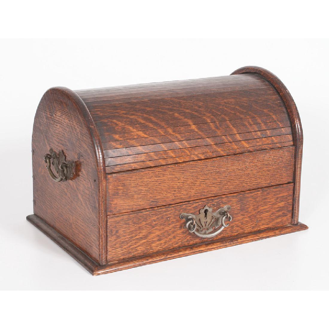 Roll Top Oak Smoking Chest: English. A tabletop chest in oak, having a domed top and single lower drawer that activates roll top, revealing two upper compartments, the drawer fitted with match strike and ashtray; ht. 8.25, wd. 1