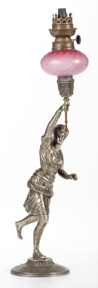Kosmos Middle Eastern Figural Oil Lamp: Continental, late 19th-early 20th century. A mixed metal oil lamp, the base featuring a Middle Eastern woman holding up a glass torch with a hand blown shade and cranberry glass well, the knob marked 