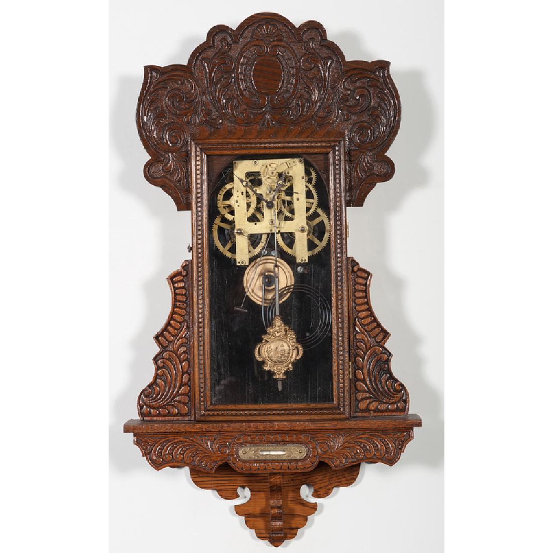 Ingraham Hanging Gingerbread Clock: American, ca 1890s. A hanging gingerbread wall clock in oak by E. Ingraham (Bristol, CT), eight-day time and strike, with Itasca label, signed movement, and built-in spirit label; ht. 28, wd. 14.25,