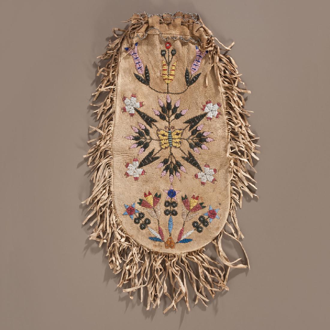 Santee Sioux Beaded Hide Pouch, Collected by Gustav: large thread-sewn pouch with draw string closure and lined with fringe along the outer edges; beaded with a floral and butterfly motif on both sides in colors of pumpkin orange, navy blue, periwinkle,