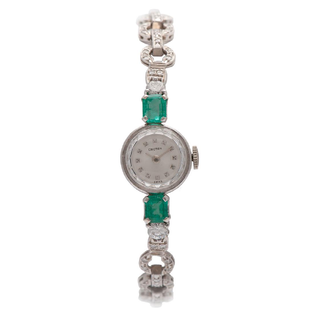 Croton Platinum and White Gold Wrist Watch: Containing two emerald cut emeralds measuring approximately 6mm x 5mm each, two round, full cut diamonds weighing approximately 0.50 carat total and 84 single cut round diamonds weighing approximately