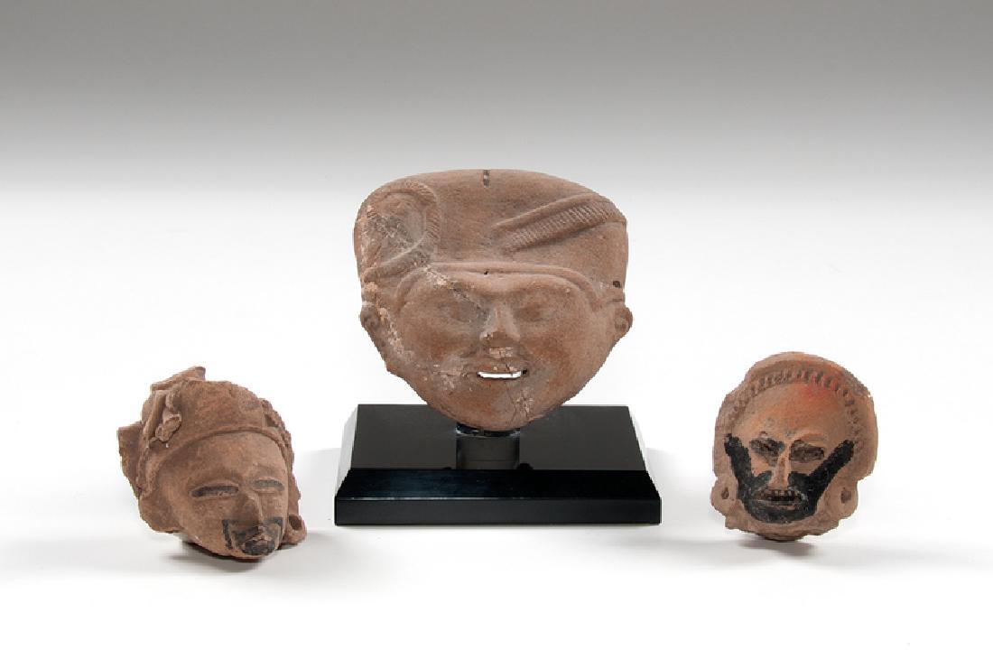 Veracruz Pottery Heads: Mexico, Veracruz, pre-Columbian. A group of three pottery heads, including one "sonriente" (smiling) face on stand, and two Remojadas heads with some black paint; sonriente (largest) ht. 5.75, wd. 6.2