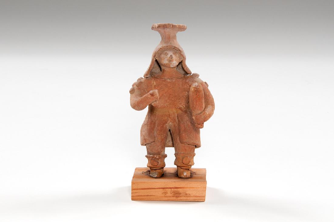 Pre-Columbian Pottery Figure, Possibly Veracruz: Mexico, possibly Veracruz, Pre-Columbian. A pottery figure, depicting a standing male with double-tapered headdress and robe, holding items in each hand, on stand; ht. 6, wd. 3.25, dp. 3 in. Provena