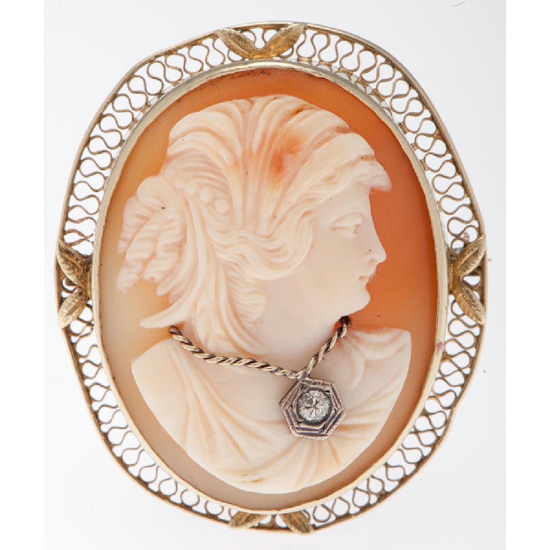 14 Karat Yellow Gold Cameo Brooch: Containing one carved shell cameo depicting a woman in profile measuring approximately 35mm x 26mm and one Old European cut diamond weighing approximately 0.06 carat. Measures approximately 1.75" L x 