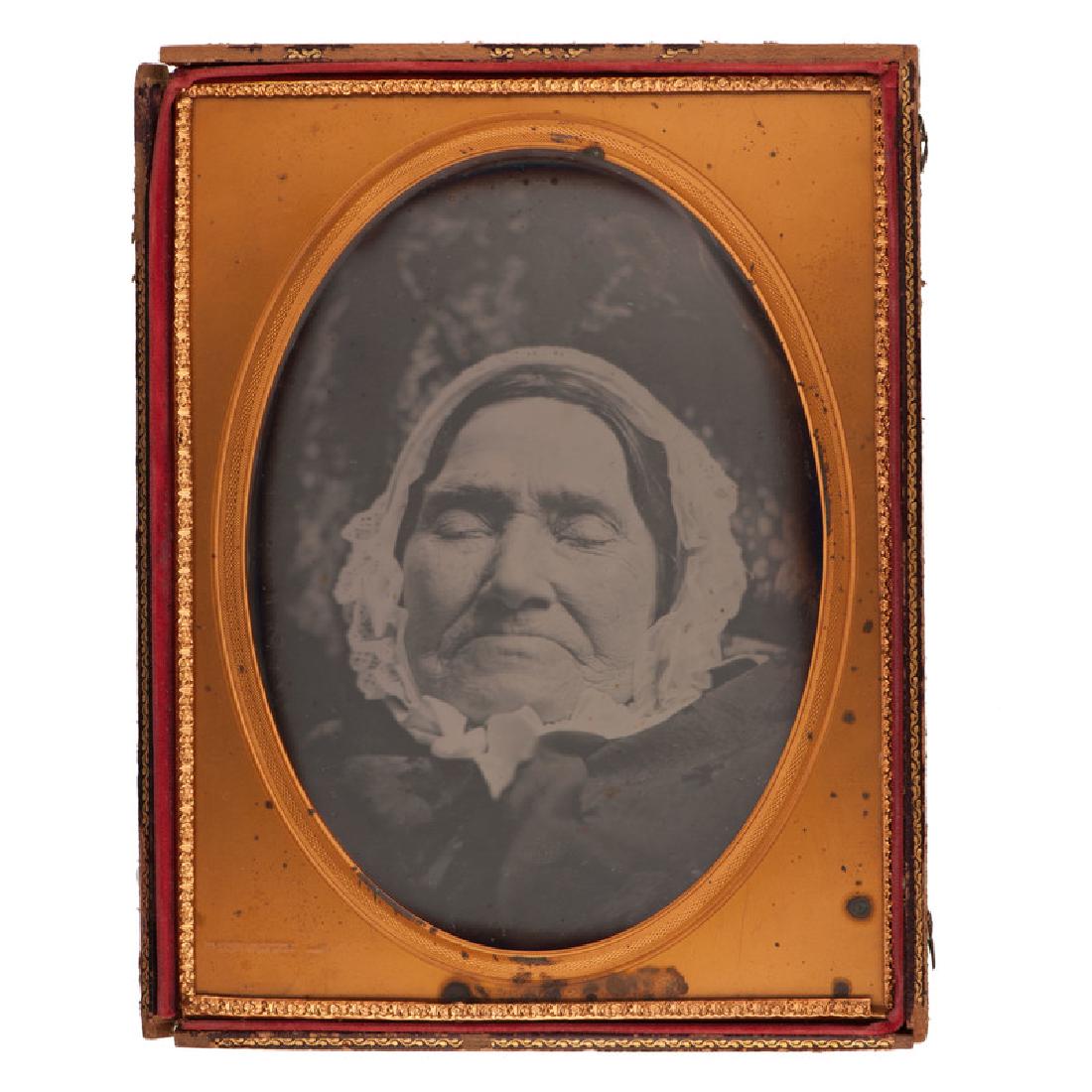 Exceptionally Rare Full Plate Postmortem Daguerreotype: Full plate daguerreotype providing an extreme close-up view of an aged woman at rest. When the mat is removed, the daguerreotype clearly shows the woman inside a coffin. With penciled date of "Oct. 