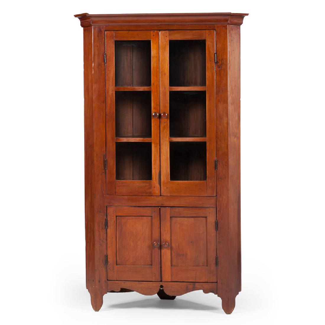 Walnut Corner Cupboard: American, 19th century. A corner cupboard in walnut, having a molded cornice, two three glass pane doors open with wooded knobs, opening to a three fitted shelf interior, above two blind paneled door 