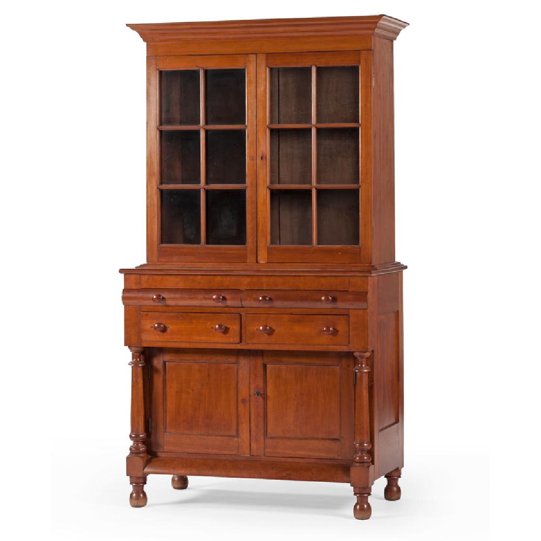 Kentucky Secretary Bookcase: American, 19th century. A two piece secretary bookcase in cherry, upper section having a molded cornice over two glass pane doors with straight mullions and interior shelves, lower transitional ca