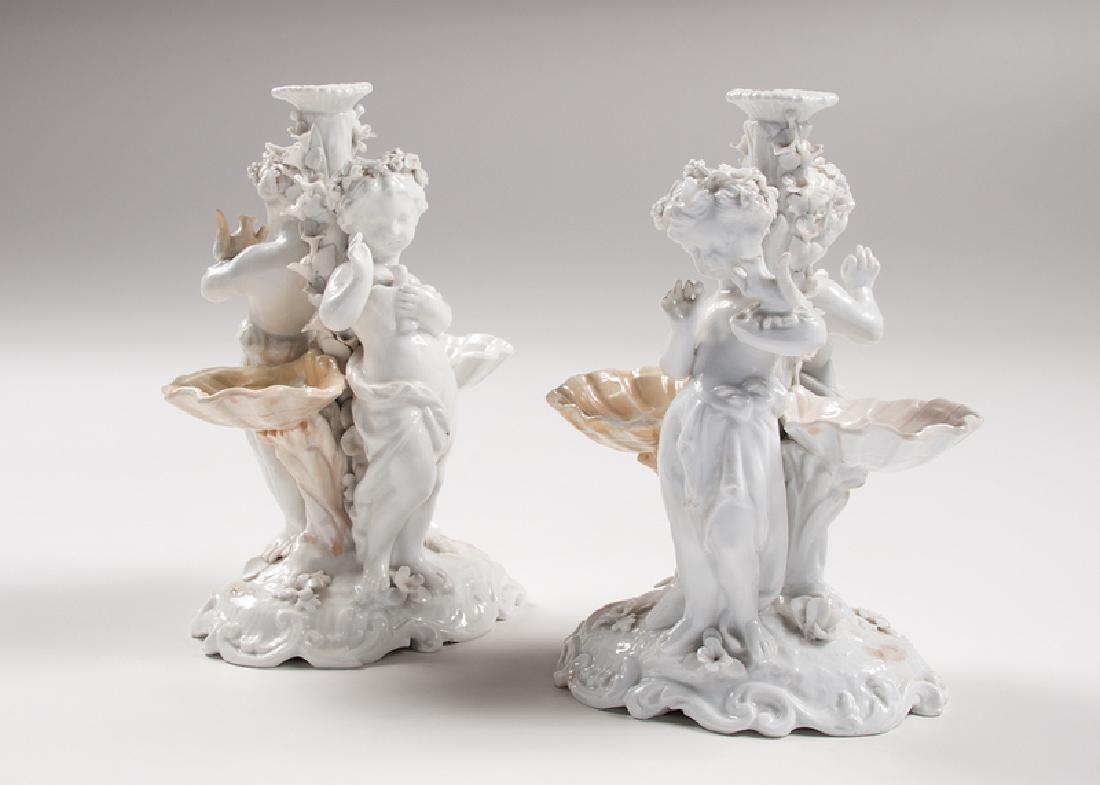 Pair Meissen Figural Candleholders: German, late 19th century-early 20th century. A pair of Meissen figural candleholders depicting putti holding woodland creatures and shells on either side, with floral decorations on stems; (each) ht.