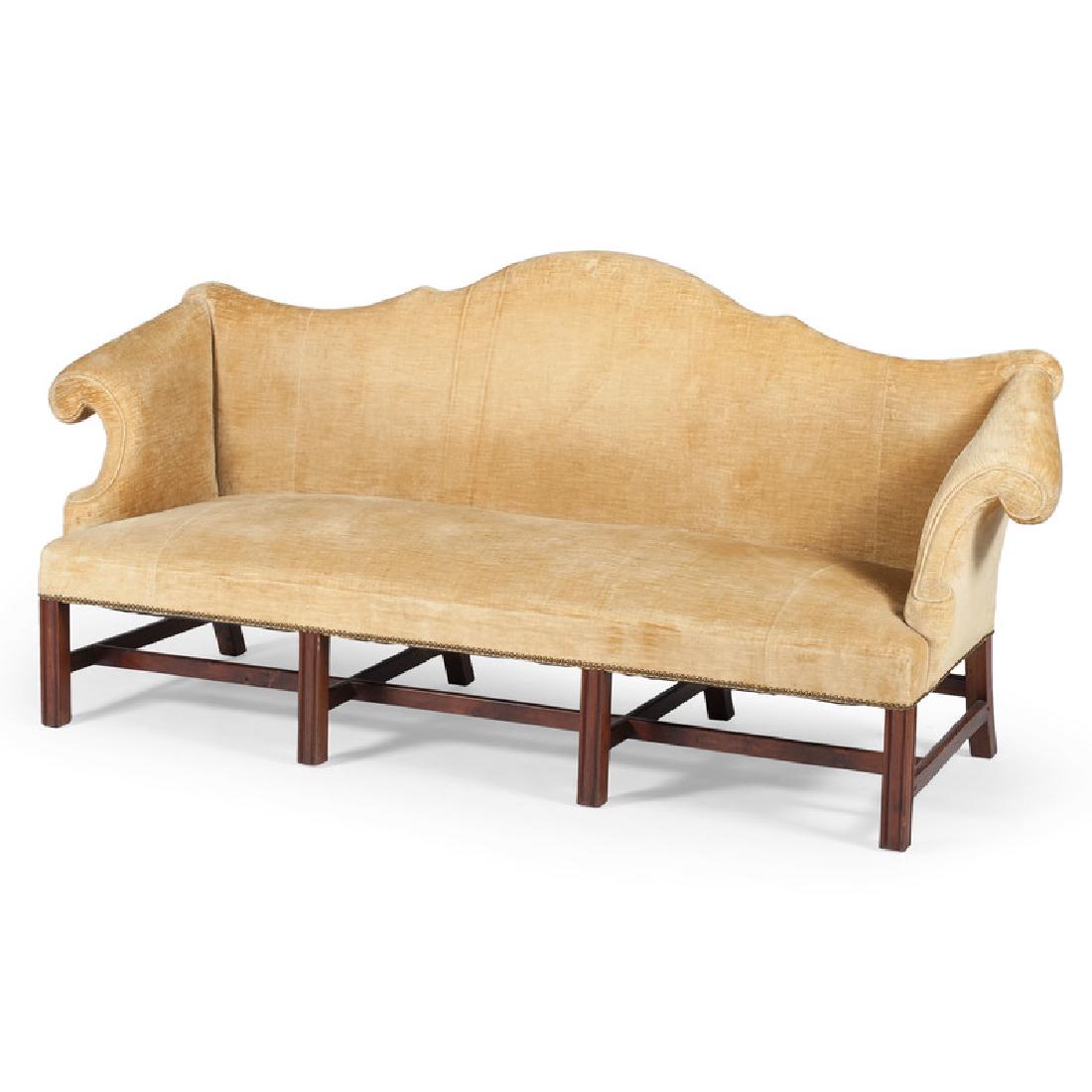 Chippendale-Style Camelback Sofa: American, 19th century. An upholstered Chippendale-style camelback sofa in mahogany, having a shaped double peak camelback crest with scrolled arms, above a straight seat rail, all rising on marlborou