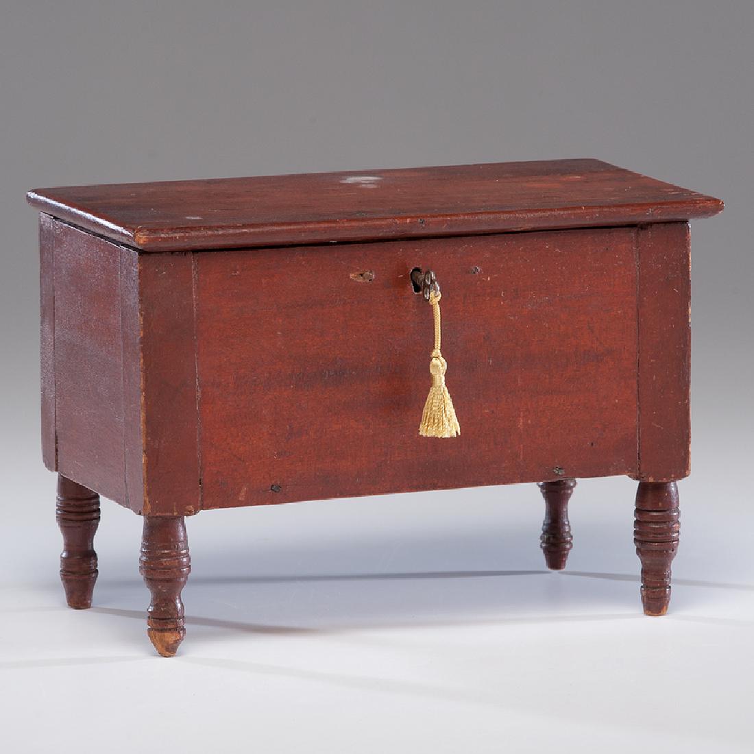 Miniature Blanket Chest in Red Paint: American, 19th century. A miniature painted blanket chest in old red paint over cherry, on turned legs and with snipe hinges; ht. 6, wd. 8.75, dp. 5 in. Provenance: Property from the Americana Collect