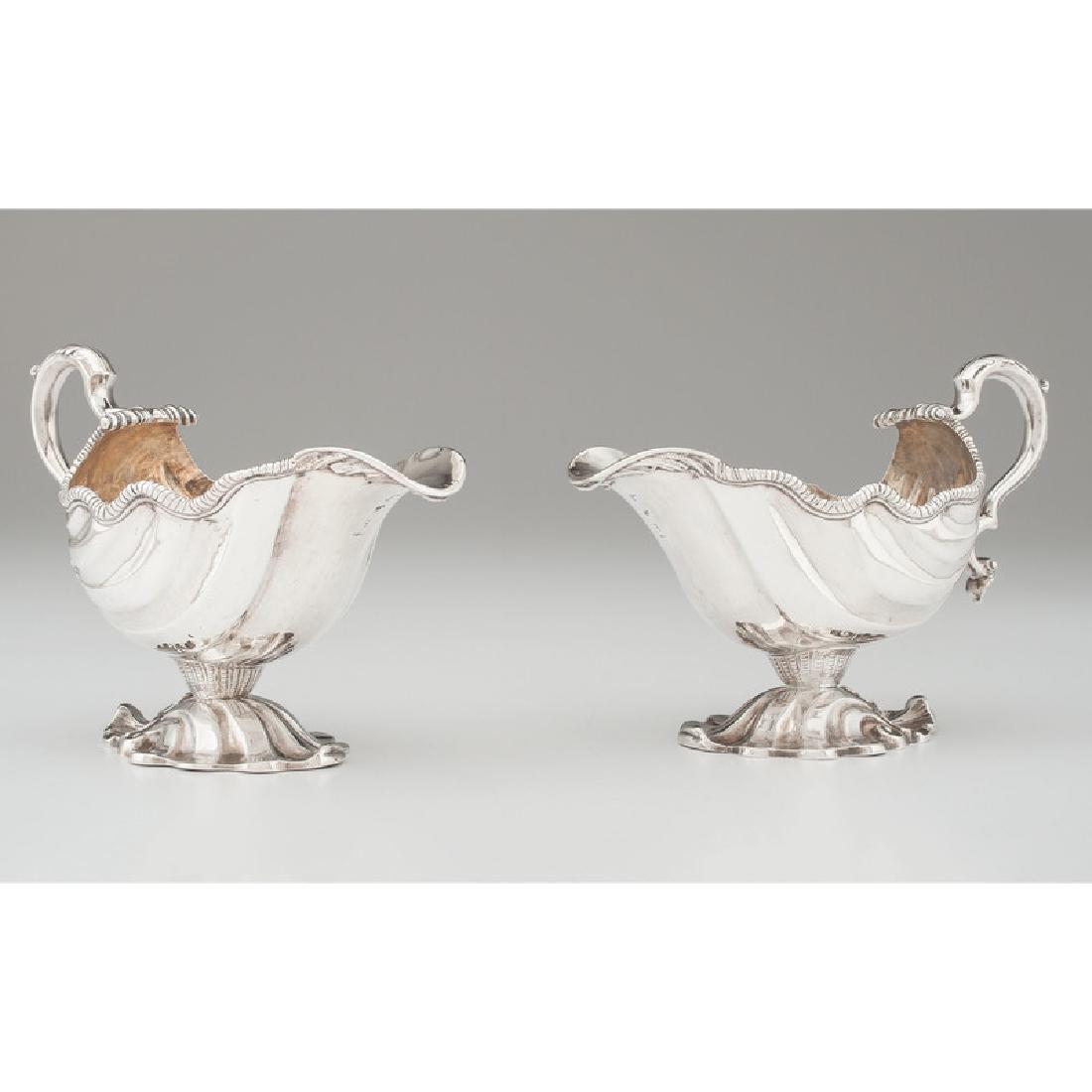 Pair of George II Sterling Gravy Boats: English, 18th century. A pair of George II sterling silver footed gravy boats, of Rococo design, each with a double scroll handle, and fluted body, partially obscured hallmarks, but likely with date m
