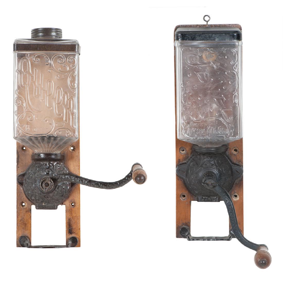 Arcade Jewel and Queen Glass and Cast Iron Coffee Mills: American. Two mounted coffee mills by Arcade with glass hoppers, cast iron grinders and tin catch cups; larger oah 14, wd. 4.5, dp. 7.75 in. (including handle and mount). The Jewel model is referenced