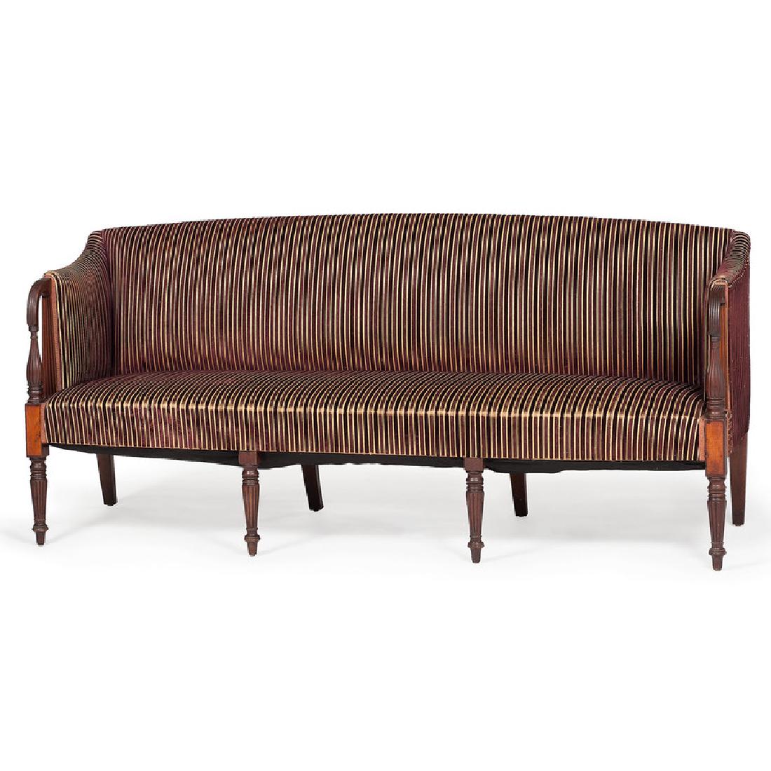New England Sheraton Mahogany Sofa: American (New England), 19th century. An upholstered Sheraton sofa in mahogany, having an arched crest, reeded arms and baluster turned supports, rising on tapering reeded and turned legs; ht. 35, wd.