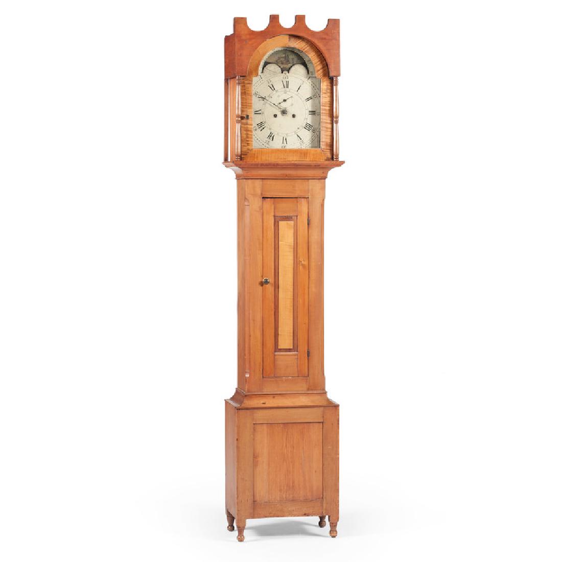 American Tall Case Clock: American, 19th century. An eight day tall case clock with painted face and lunette featuring a landscape and ship moon phase, the removable bonnet top with four plinth crest and tombstone shaped door,