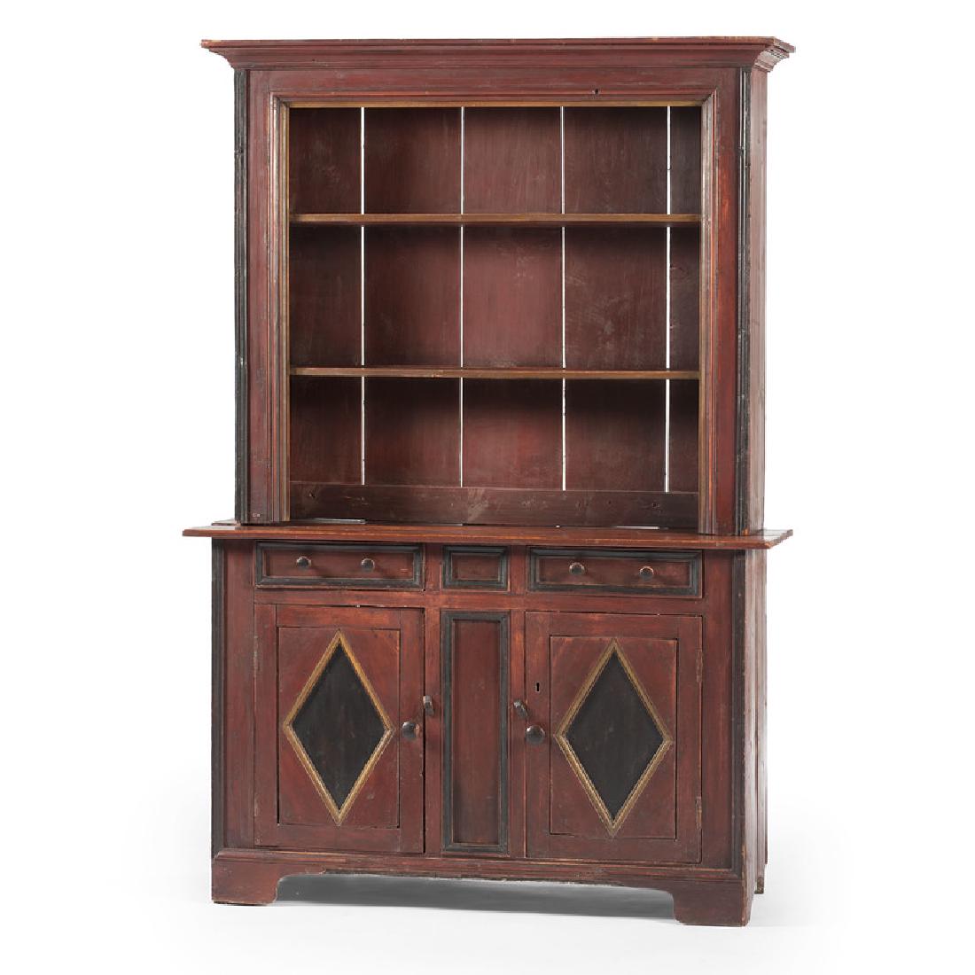Canadian Painted Stepback Cupboard: Canadian, 19th century. A two-piece stepback cupboard in red and black paint with gold accents, the upper case having a molded cornice, single board sides, and step molded case with open shelving, the