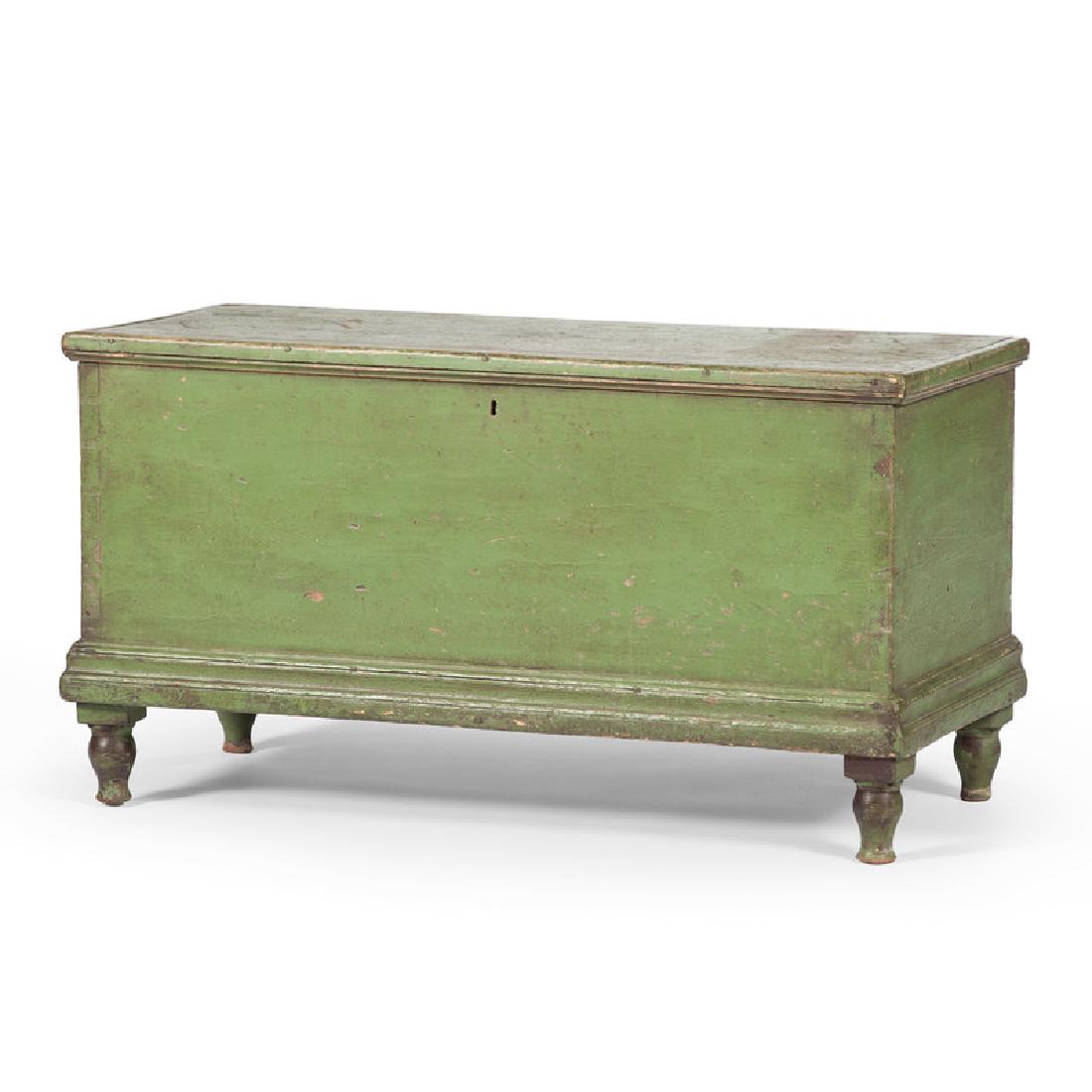 Western Reserve Blanket Chest in Green Paint: American, ca 1830. A painted blanket chest in poplar and green paint, having a molded lift top surface with open interior and right till, above a dovetailed case, rising on turned legs; ht. 19.5, wd. 