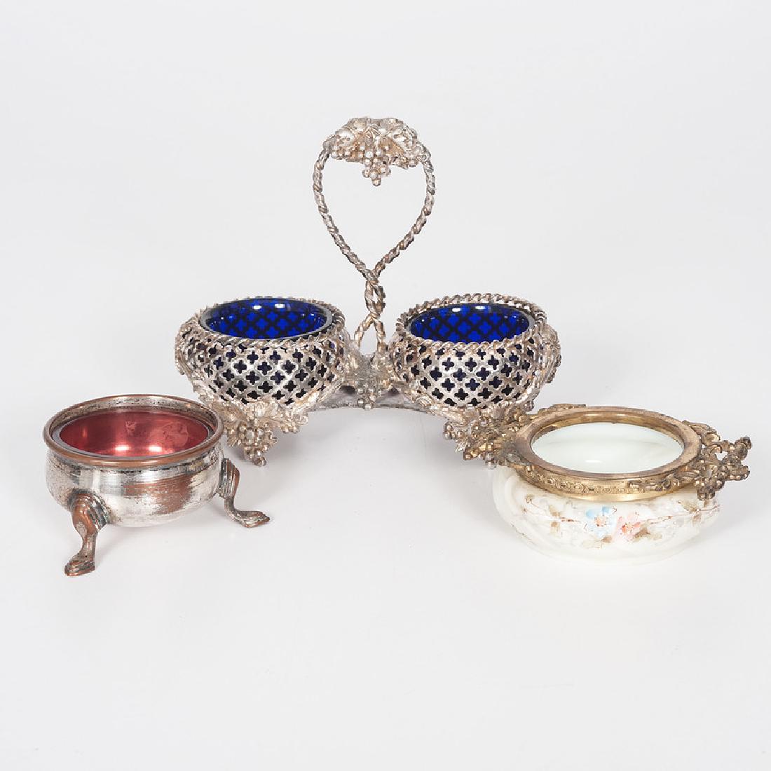 Silverplate and Milk Glass Salt Cellars: 19th-early 20th century. A silverplated double master salt with reticulated bowls and grape motifs, unmarked, with cobalt glass liners, a single silverplated salt with illegible mark and ruby glass li