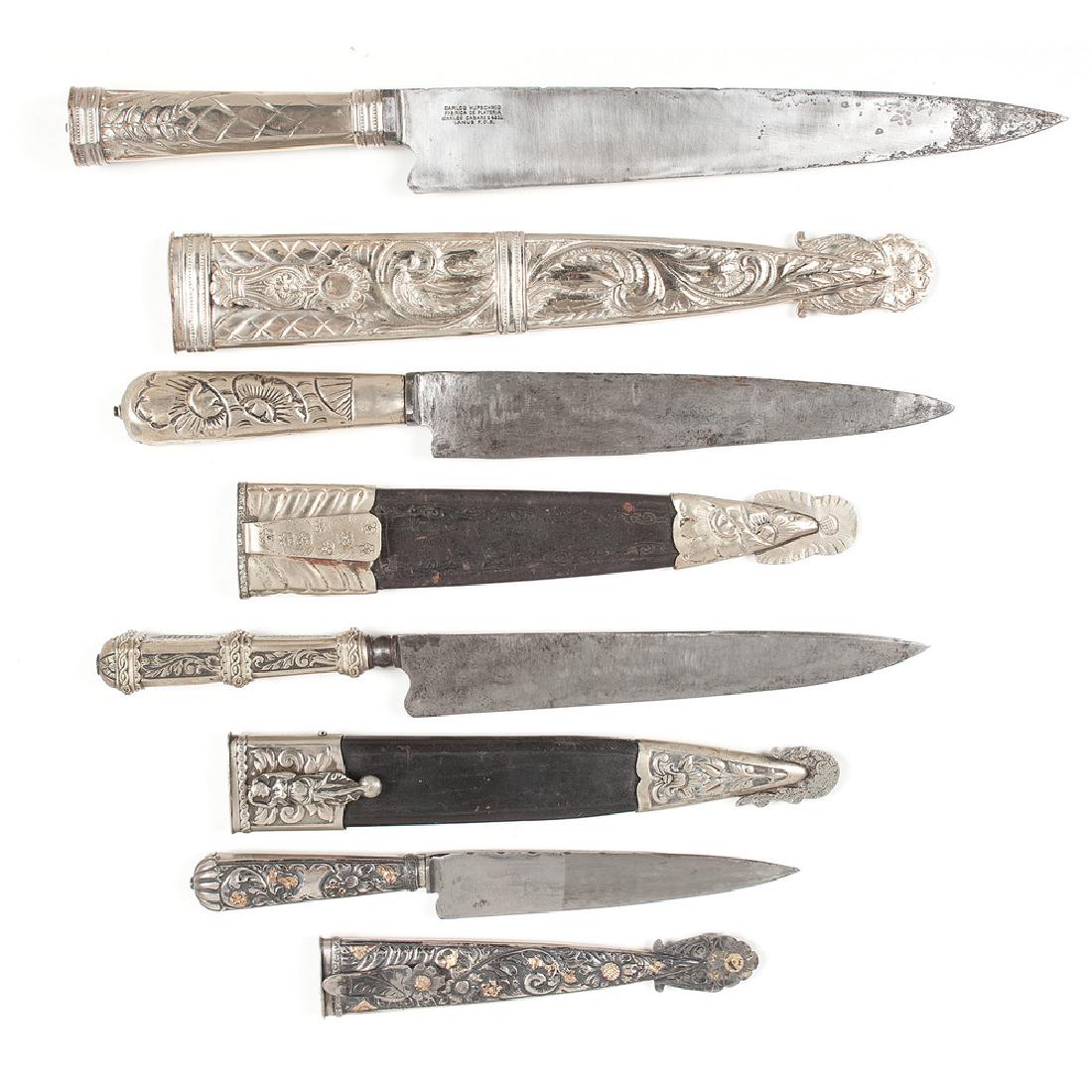 Lot of Four Argentinian Gaucho Knives, including Carlos: Lot consists of four Argentinian Gaucho knives with blade lengths ranging from 6.5" to 11", two with German made blades. All have silver mounts with foliate and firgural designs. Two examples have met