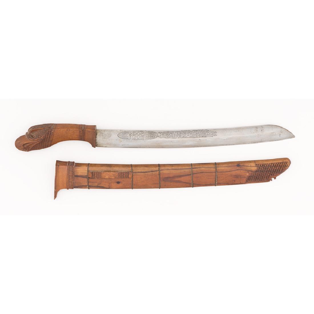 Indonesian Golok Machete, Dated 1893: wood handle carved with the image of a bird; wood sheath; blade with decoration and inscribed date, overall length 22 in., length of blade 13.75 in. 1893