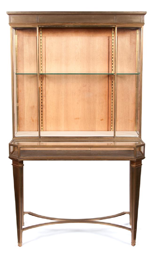 Escalier de Cristal Bronze Vitrine: French, early 20th century. An Escalier de Cristal step-back vitrine in bronze, the upper case illuminated, the lower with lift top, all rising on straight legs connected by curved X-shaped stret