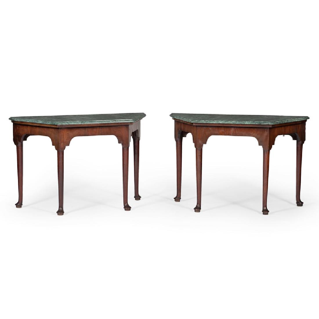 Pair of Georgian Console Tables with Marble Tops: English, 18th century. A pair of console tables in mahogany, each having a shaped Verona marble top surface, conforming case with plain frieze, all rising on round tapering legs with padded feet;